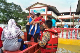 A woman carries a child into a boat as they are evacuated by rescue officials as floodwaters rise in Shah Alam, Selangor, Malaysia