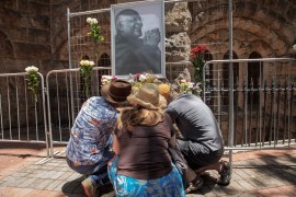 People lay flowers beneath a picture of the Archbishop Desmond Tutu in Cape Town
