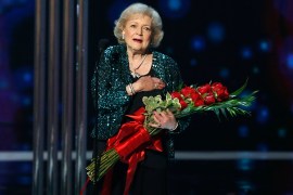 Actress Betty White holds flowers while standing on stage at the People's Choice awards