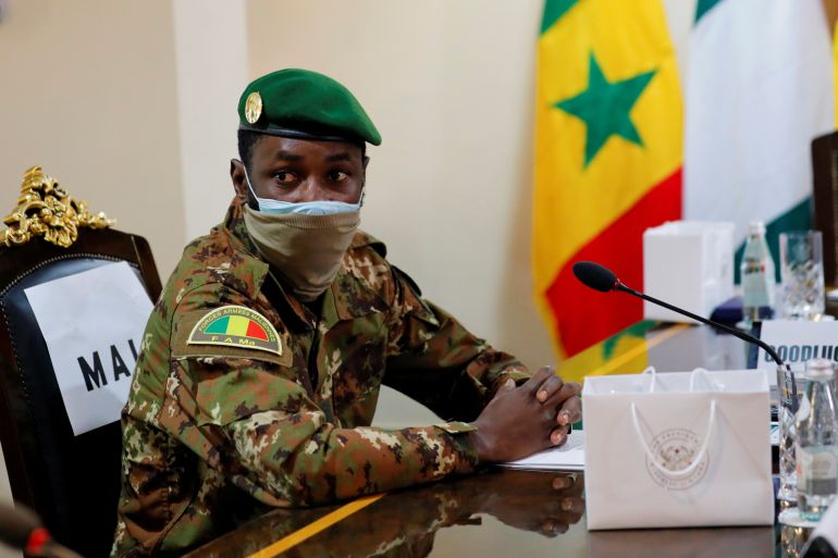 Colonel Assimi Goita is seen sitting at a desk in front of a microphone with a mask on