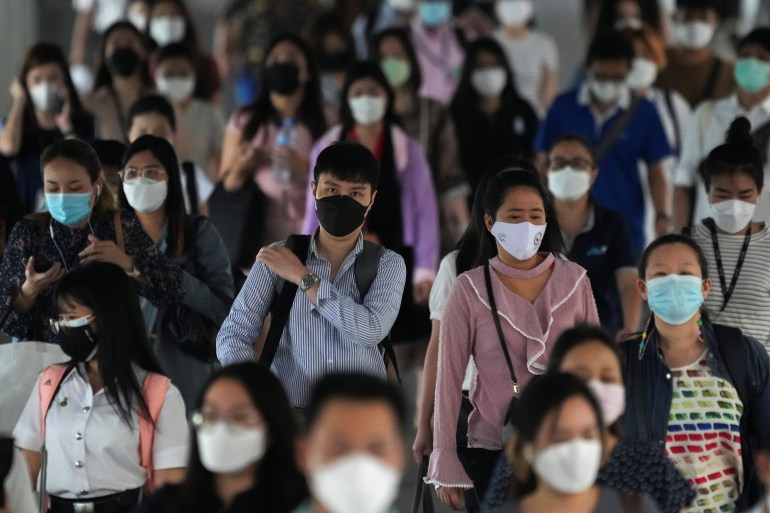 A crowd of people wearing face masks at a train station in Bangkok, Thailand