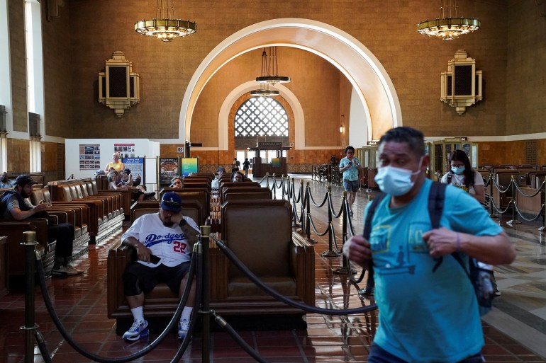 A traveller wearing a protective mask walks past a waiting area