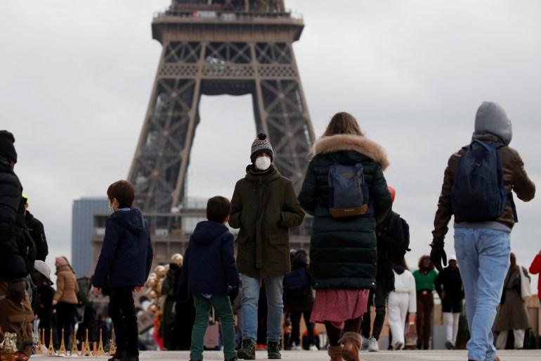 People, wearing protective face masks, walking near the Eiffel Tower in Paris