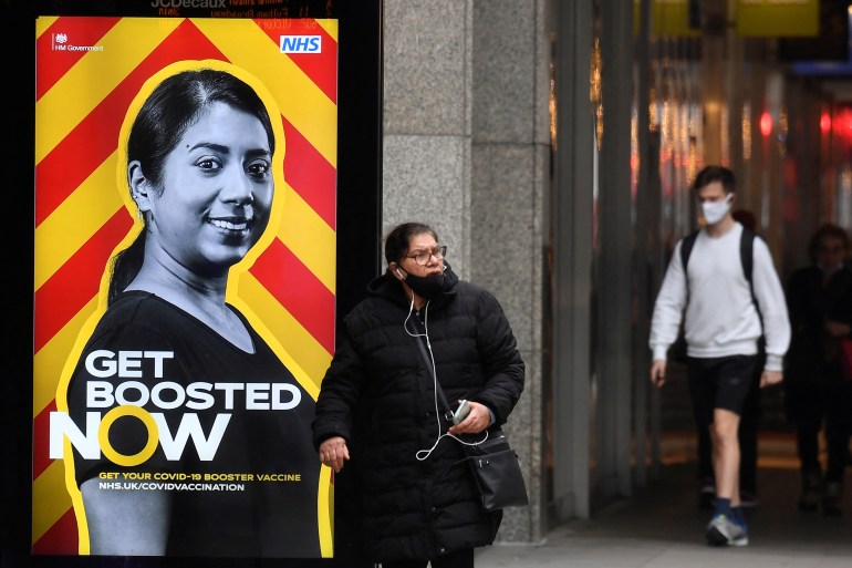 People walk past a government health campaign advertisement encouraging people to take a coronavirus disease (COVID-19) vaccine booster dose, at a bus stop, amid the spread of the COVID-19 pandemic, in London, Britain, December 17, 2021