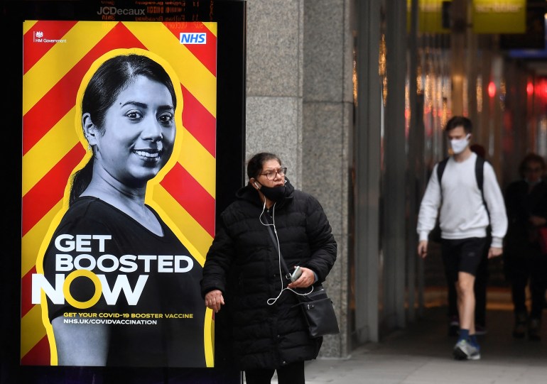 People walk past a government health campaign advertisement encouraging people to take a coronavirus disease (COVID-19) vaccine booster dose, at a bus stop, amid the spread of the COVID-19 pandemic, in London, Britain, December 17, 2021