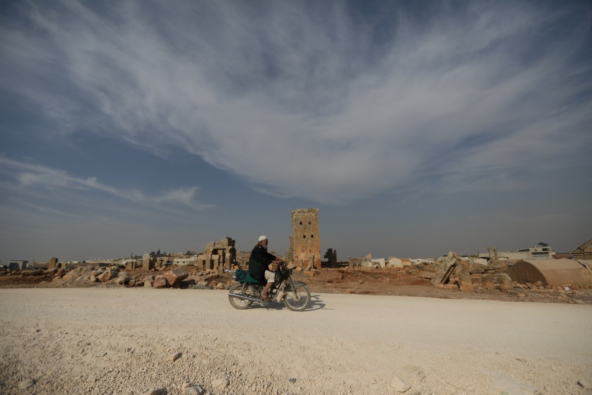 A man rides a motorcycle through the archaeological site of Sarjableh, Syria