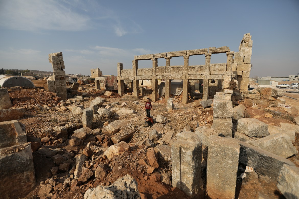 A child stands in the middle of ruins of an ancient building in the archaeological site of Sarjableh, Syria
