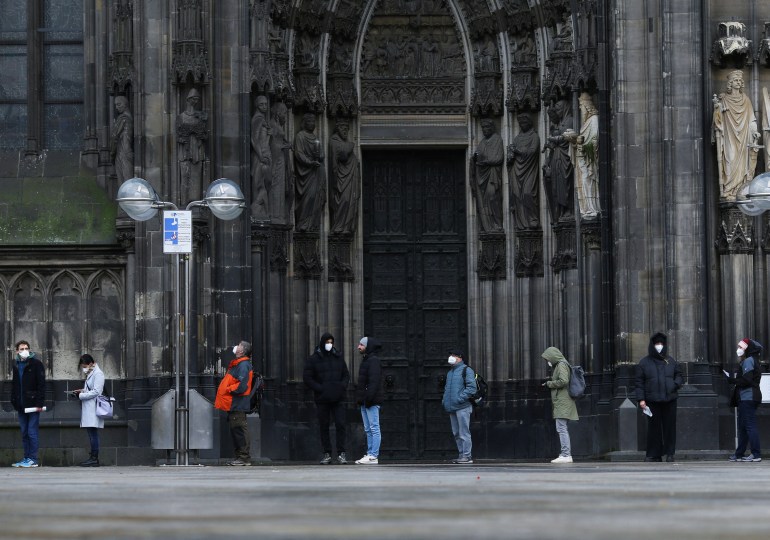 People queue outside of Germany's Cologne Cathedral to receive a dose of COVID-19 vaccine