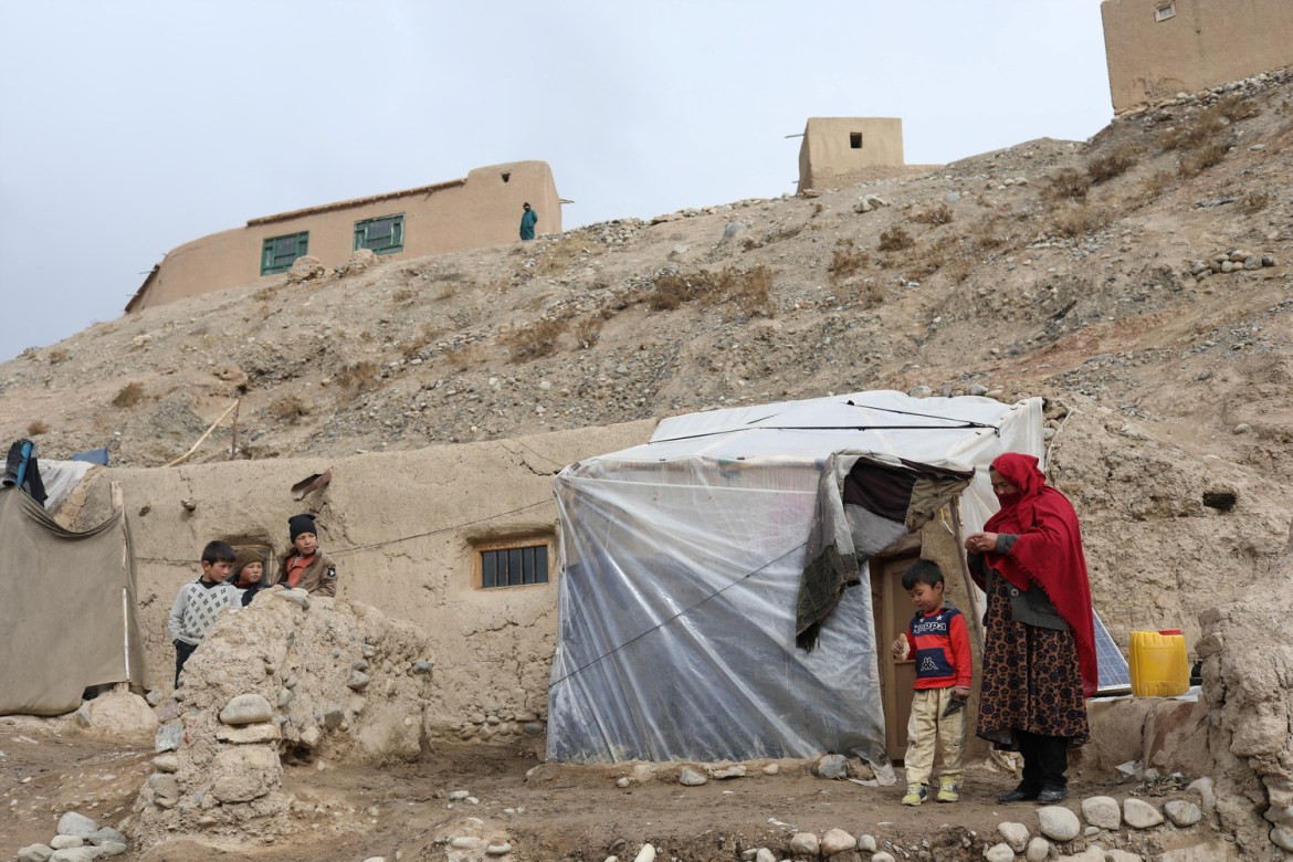 Razia, stands with one of her children in front of their home in Bamiyan