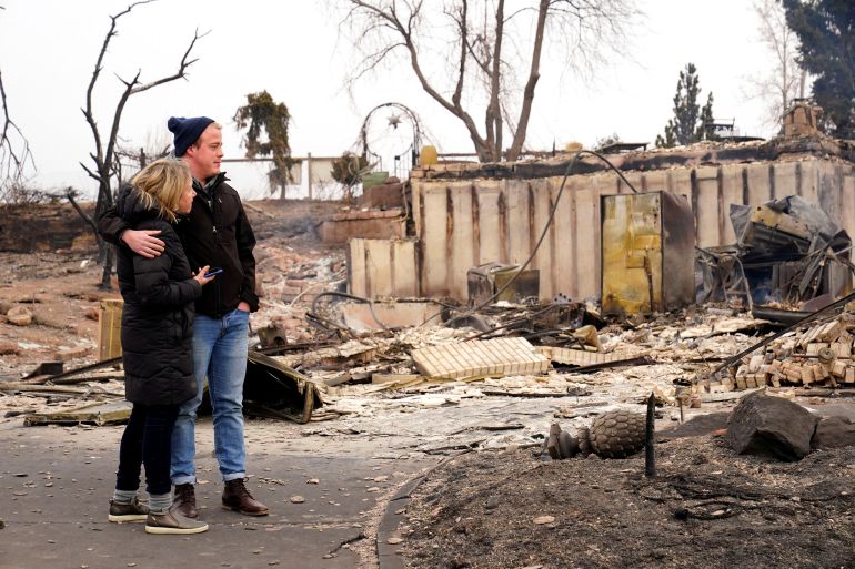 A couple looks at damage to their home after wildfires ripped through Colorado