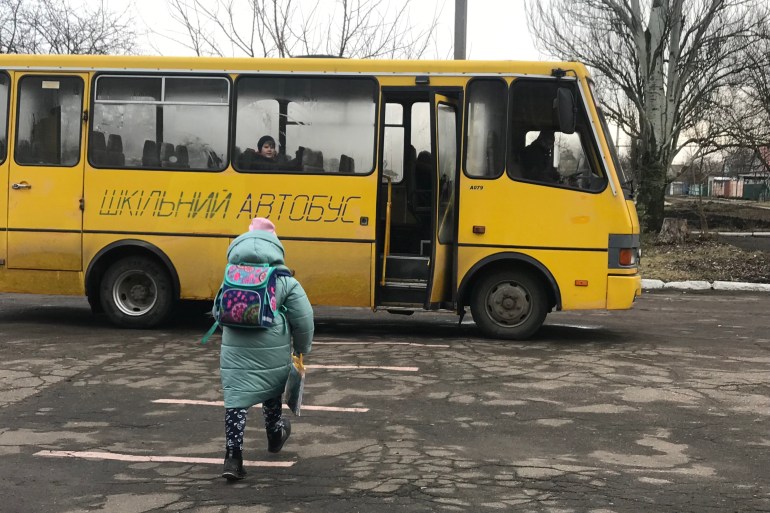 Uma criança pegando o ônibus escolar para levá-la da escola para casa em Pervomaiske
