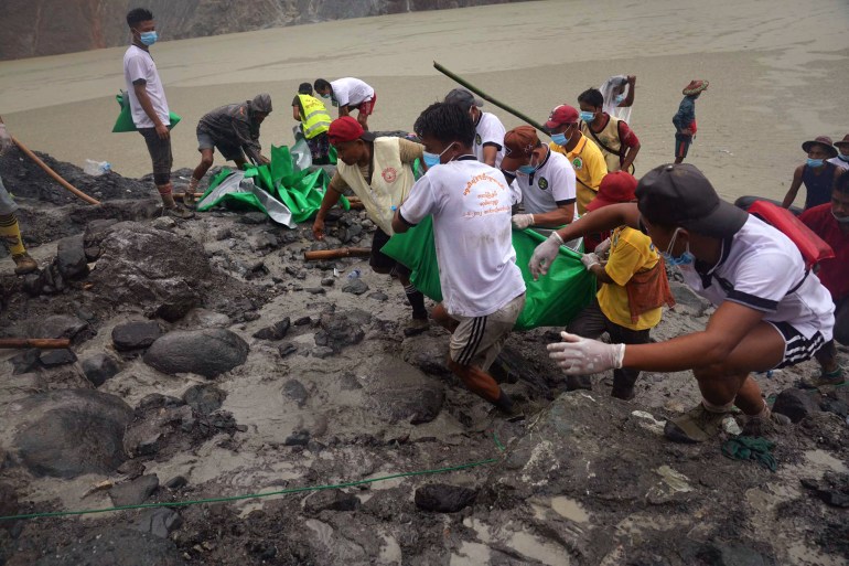 People pull a green plastic that shrouds a recovered body Friday, July 3, 2020 in Hpakant, Kachin State, Myanmar. Over 100 people were killed Thursday in a landslide at a jade mine in northern Myanmar, the worst in a series of deadly accidents at such sites in recent years