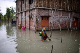 Villagers wade through waist-deep waters to reach their homes