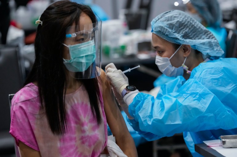 یک زن از یک کارمند بهداشتی در تایلند واکسن دریافت می کند