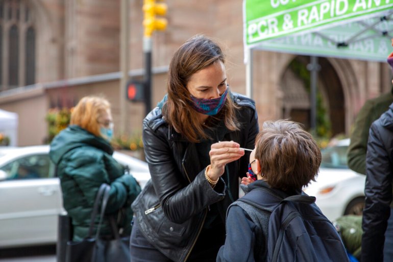 A woman swabs her son's nose for a COVID test at a pop-up site in New York City