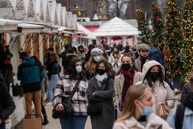 Pedestrians wearing masks are seen walking at an outdoor Christmas market in Paris, France
