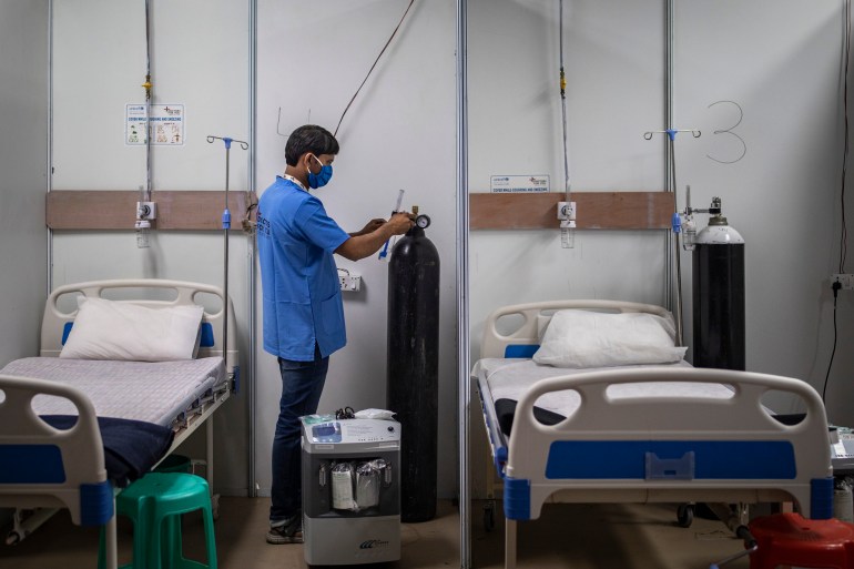 A paramedic checks an oxygen cylinder at a makeshift COVID-19 care center at an indoor sports stadium in New Delhi
