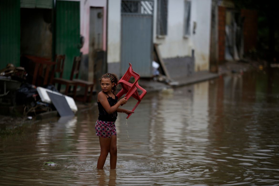 A girl carries a chair in flood waters in Bahia state, Brazil