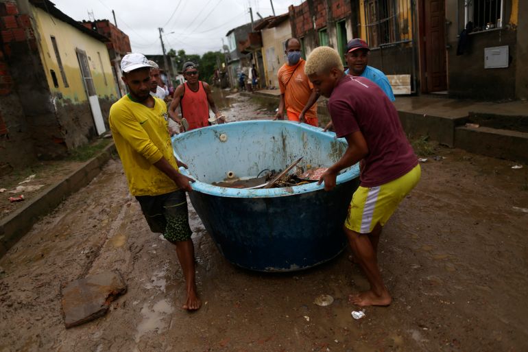 Residents use a bathtub as a container to carry away items from their flooded homes in Itapetinga, Bahia state, Brazil