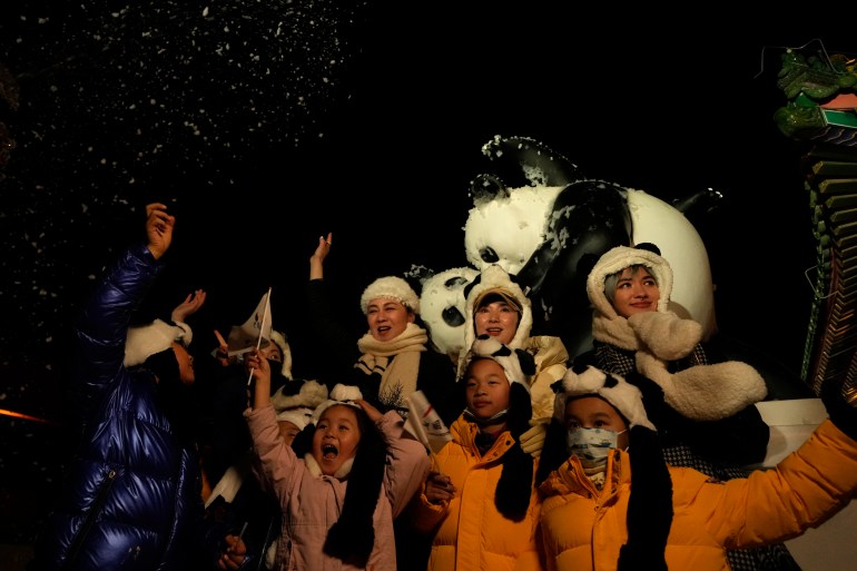 Attendees at an event held outside that coincided with the New Year Eve cheer as fake snow from a foam machine is blown overhead in Beijing, China