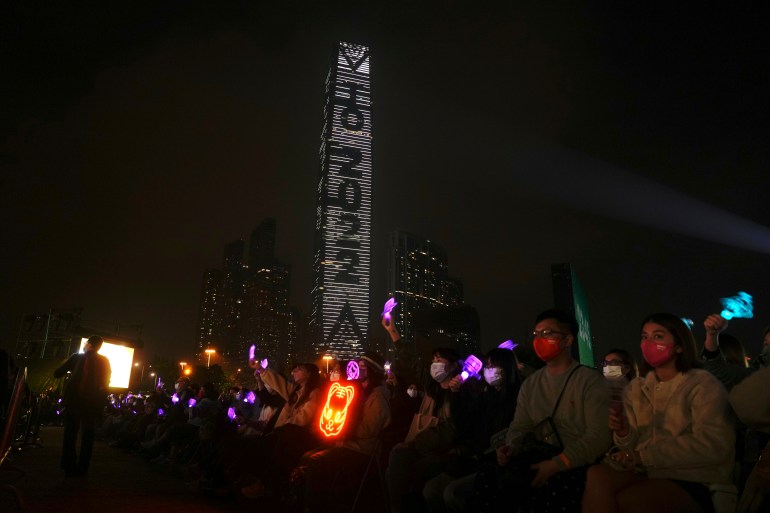 People sit on chairs outside and watch a performance at a New Year's Eve concert in Hong Kong