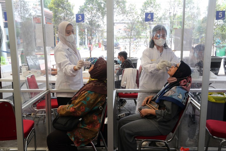 Health workers administering coronavirus swab tests at the Pasar Senen train station in Jakarta