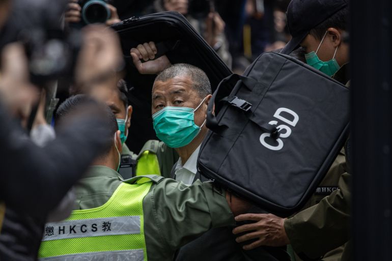 Hong Kong media tycoon Jimmy Lai entering Hong Kong's top court. He is wearing a face mask. There are lots of people around him