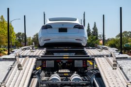 A Tesla Model 3 vehicle on an auto carrier in front of a store in Rocklin, California, United States