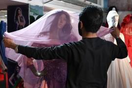 A shopkeeper arranges a bridal dress displayed on a mannequin garment shop in Kabul