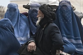 Afghan women wearing the blue burqa ride in a vehicle.