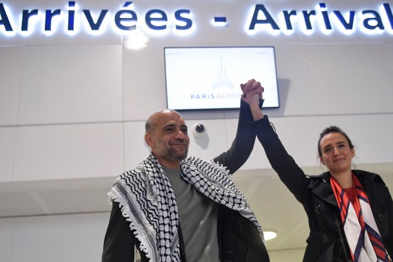 Egyptian-Palestinian activist Ramy Shaath holds up the arm of his wife Celine Lebrun-Shaath as he arrives at Roissy Airport in Roissy, outside Paris, on January 8, 2022.