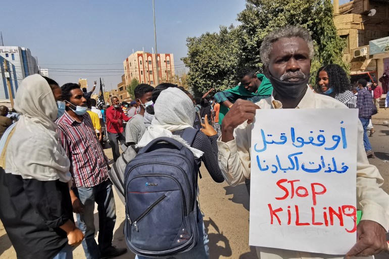 A Sudanese protester holds a sign that says in English and Arabic 'Stop Killling'