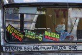 Sign that reads &#34;No Vaccine No Ride&#34; (L) is seen on the windshield of a passenger jeepney in Quezon City, suburban Manila [Jam Star Rosa/AFP]