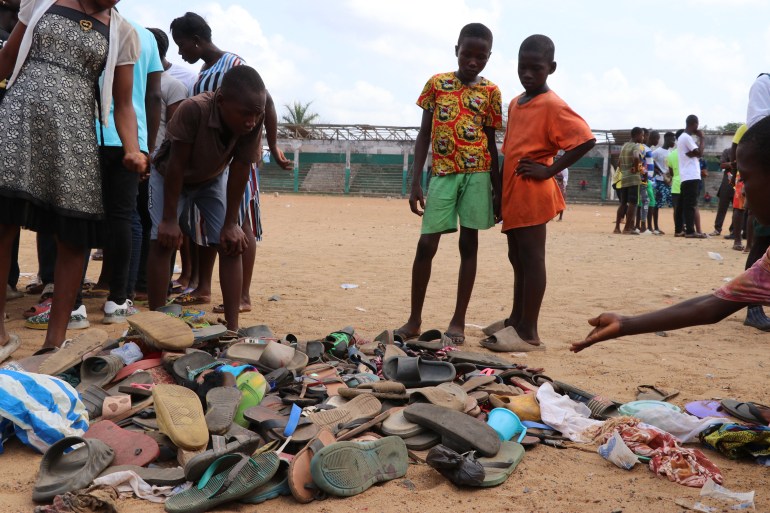 People search through piles of shoes left at a field in Monrovia, on January 20, 2022, where 29 people, including a pregnant woman and 11 children are confirmed dead after a stampede broke out at a Christian crusade on the night of January 19, 2022. - A stampede started after a group of men carrying knives tried to rob worshippers. (Photo by EMMANUEL TOBEY / AFP)