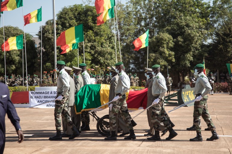 Malian Military guards wheel in the coffin of the late ousted President of Mali, Ibrahim Boubacar Keita