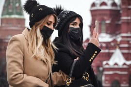 Tourists wearing face masks walk along the Red Square in central Moscow