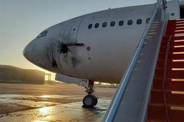 a damaged stationary aircraft on the tarmac of Baghdad airport