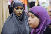 A woman walks past a dummy covered with a veil at a stand [File: Bertrand Guay/AFP]