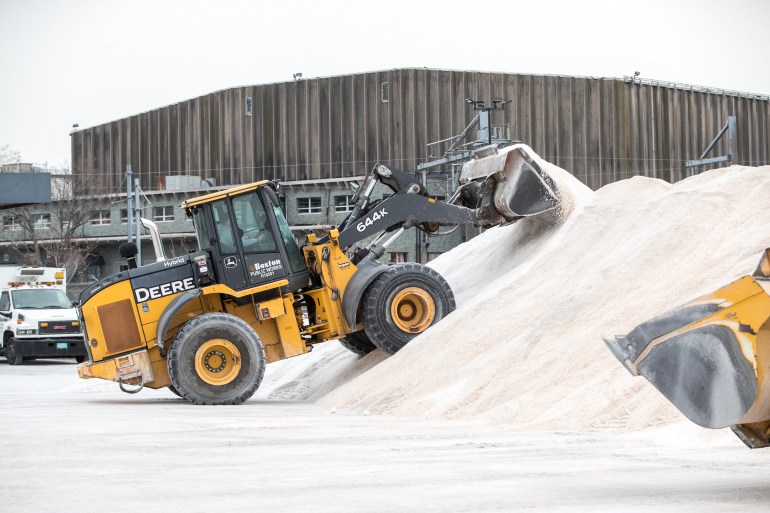 An excavator piles road salt in preparation for Winter Storm Kenan at the Boston Public Works Department yard