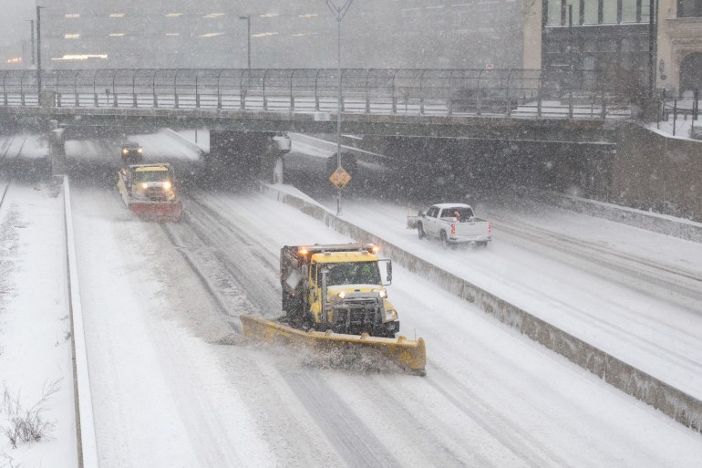 snow plows drive down a snow-covered highway