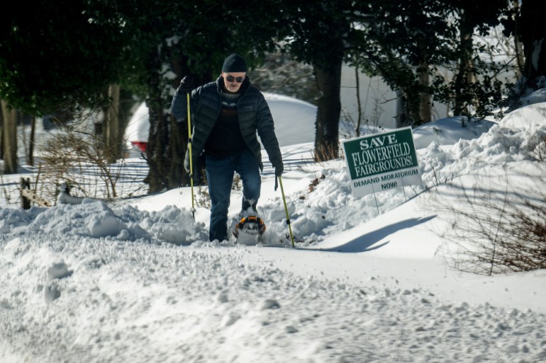 A man walks with snow shoes after a blizzard hit the Northeast in Centereach, New York