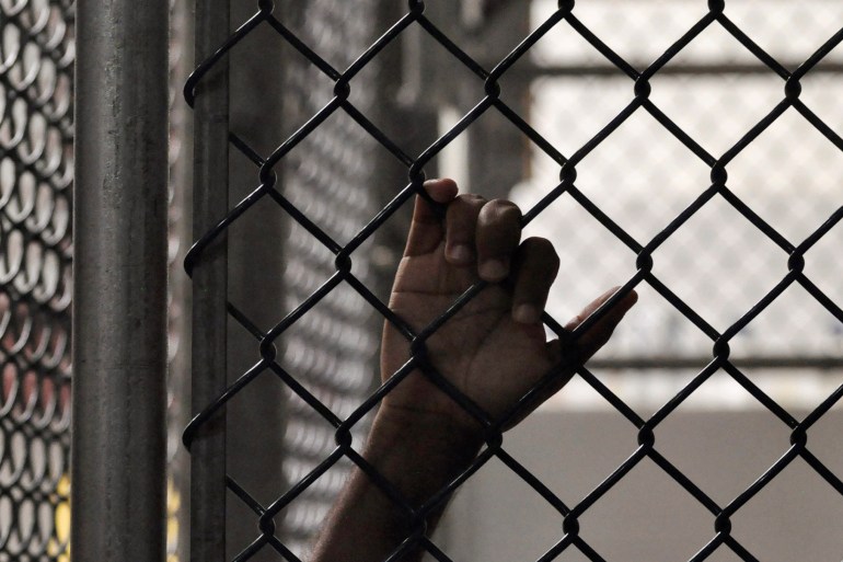A Guantanamo detainee holds onto a fence inside the Camp 6 high-security detention facility