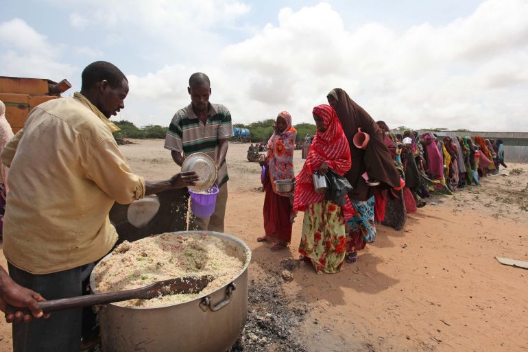 Internally displaced Somali people stand in a queue waiting to be served with cooked food in Hodan district south of capital Mogadishu