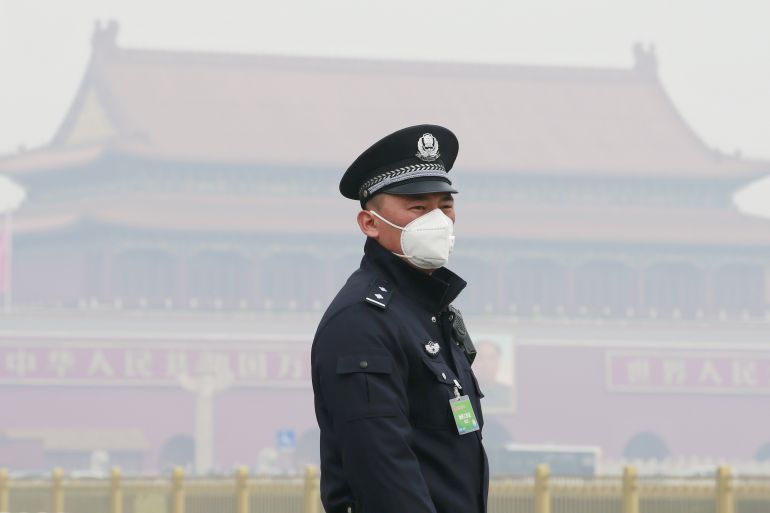 A policeman, wearing a mask to protect from severe pollution, secures the area near the Great Hall of the People in Beijing