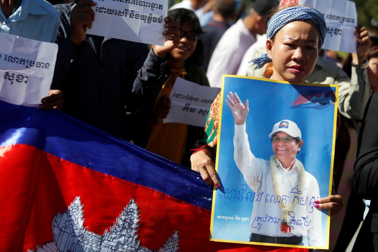 A female supporter of Kem Sokha holds his photograph as another person holds a Cambodian flag during a rally in support of the former leader of the opposition