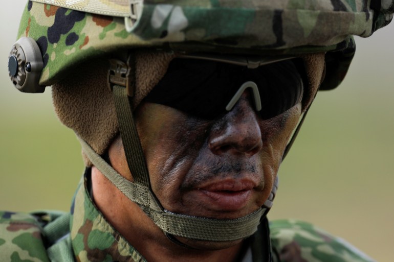 A Japanese soldier, his face covered in camouflage paint, takes part in military exercises with the US