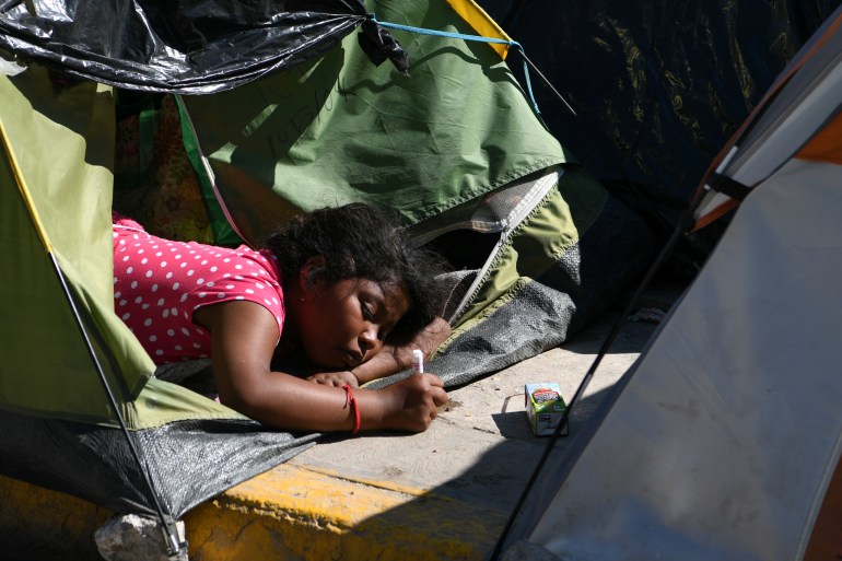 Migrant girl laying out of a tent on the sidewalk