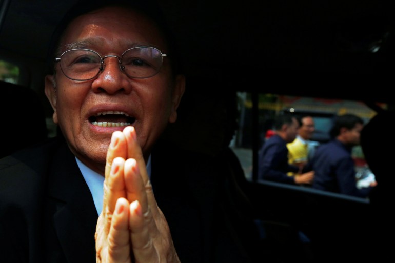 Kem Sokha, wearing a dark suit and sitting in a car with his hands pressed together in a traditional Cambodian greeting after leaving court during a previous case