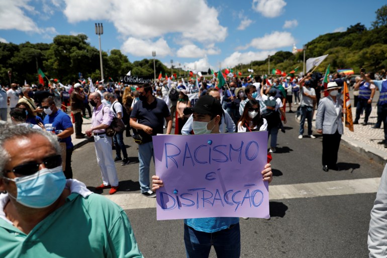 A supporter of Portugal's far-right Chega party holds a placard reading "racism is distraction" 