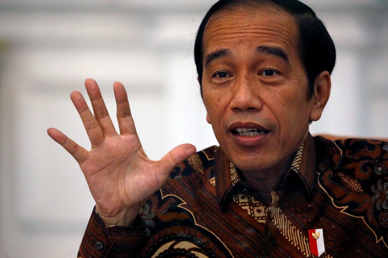 Președintele indonezian Joko Widodo, îmbrăcat într-o cămașă maro batik, explică un punct în timpul unei conversații